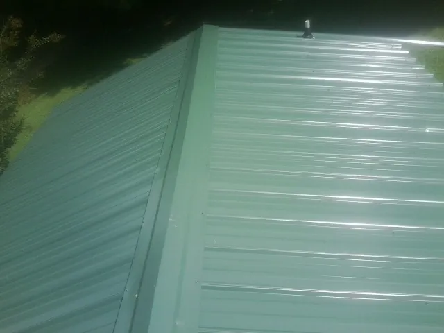 New green metal panels meeting at the ridge of a roof — Flat Roof Repair work by our crew in Plaistow