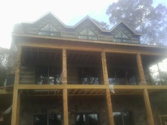 Dormers and porch framing on a large log home under construction — Roof Coating work by our crew in Plaistow