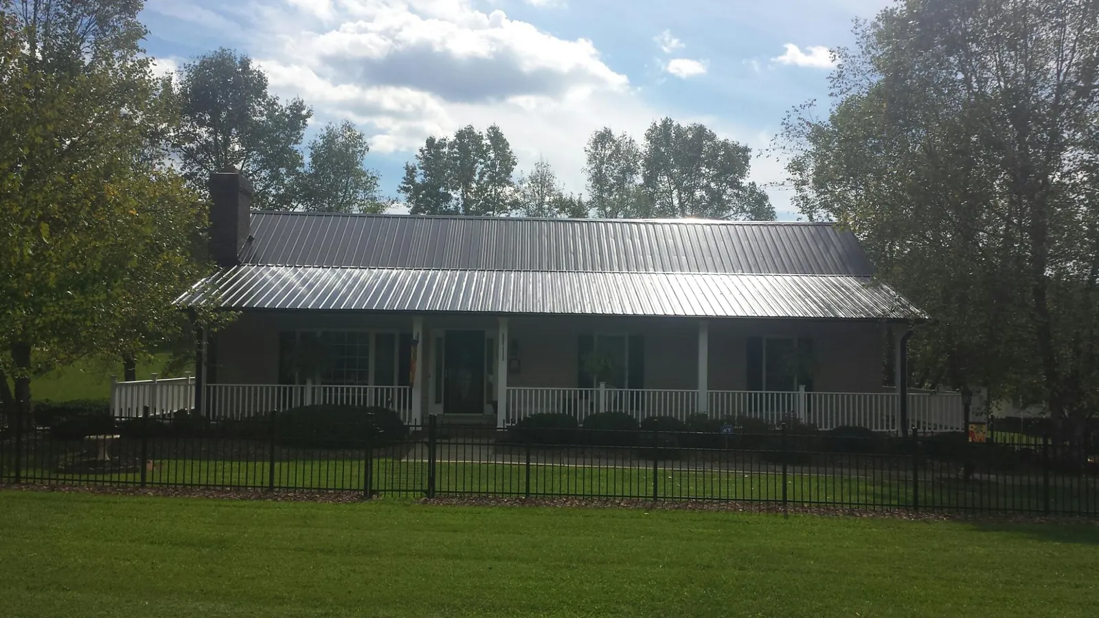 Gray metal roof on a brick ranch with a full width front porch — Gutter Guard Installation work by our crew in Plaistow