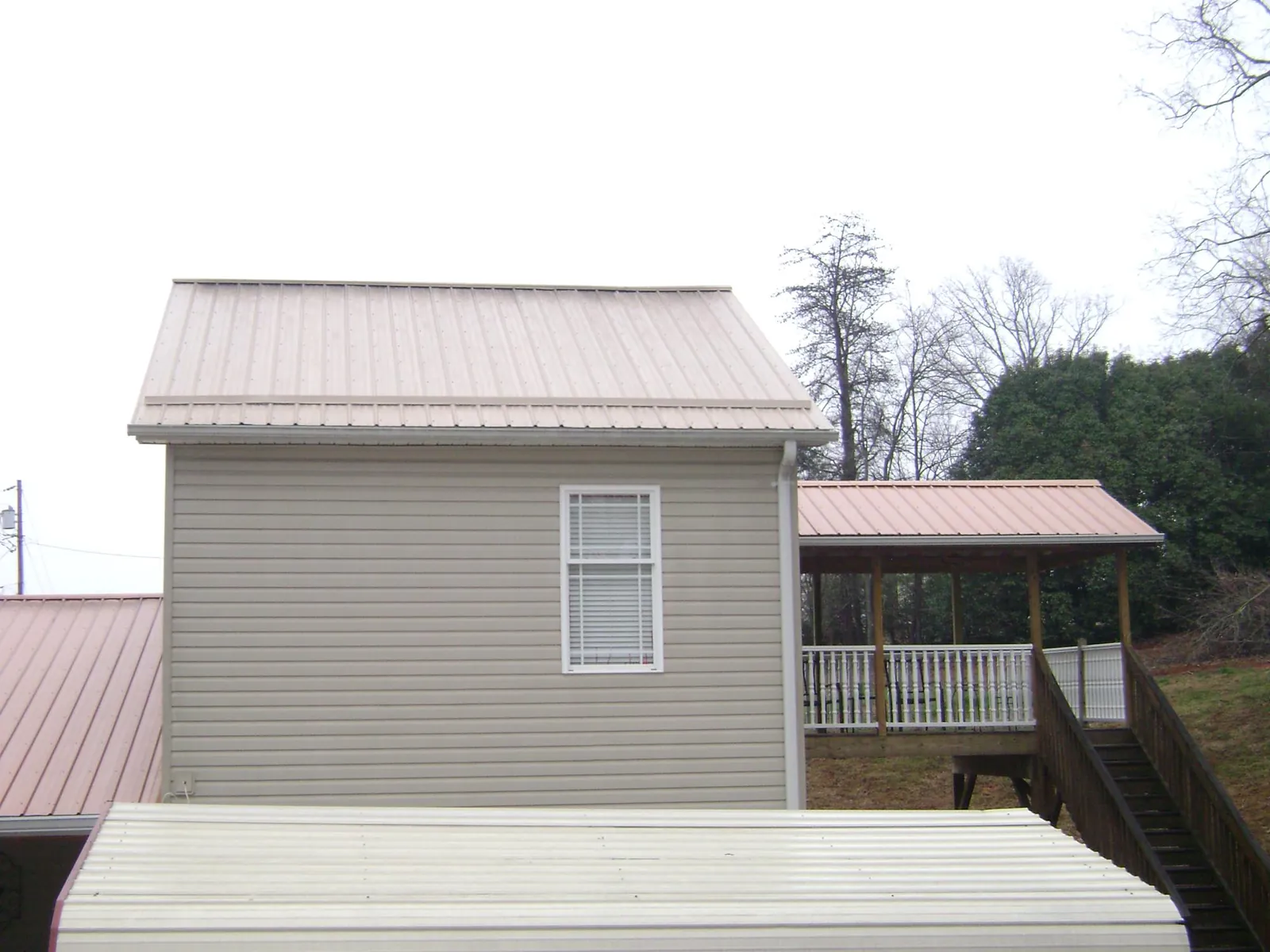 Tan metal roofs on a two story addition and attached porch, from a Roof Replacement job in Plaistow