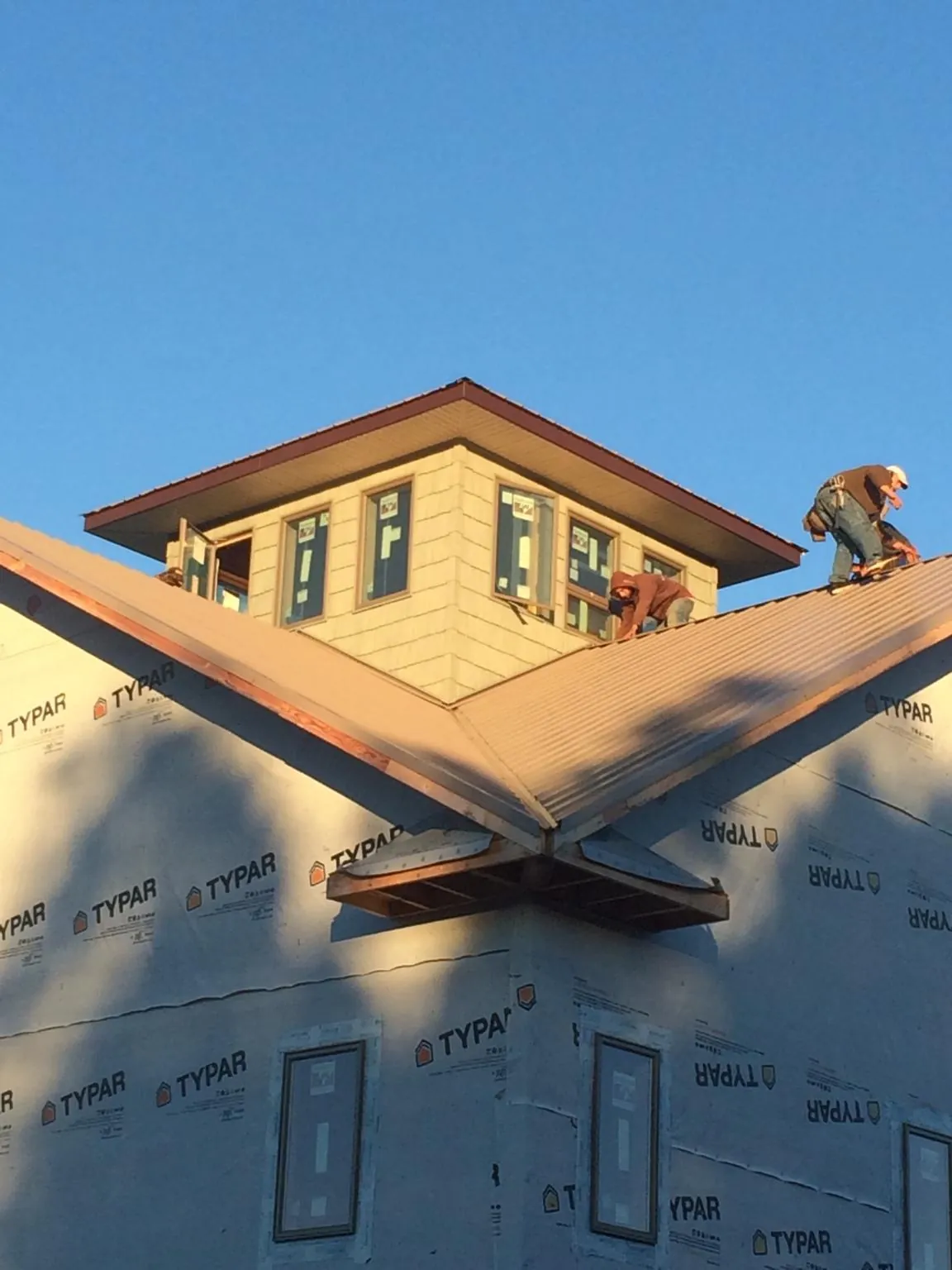 Roofers working around a rooftop cupola on a new metal roof at sunset — Roof Waterproofing in Plaistow by Roofing Brothers